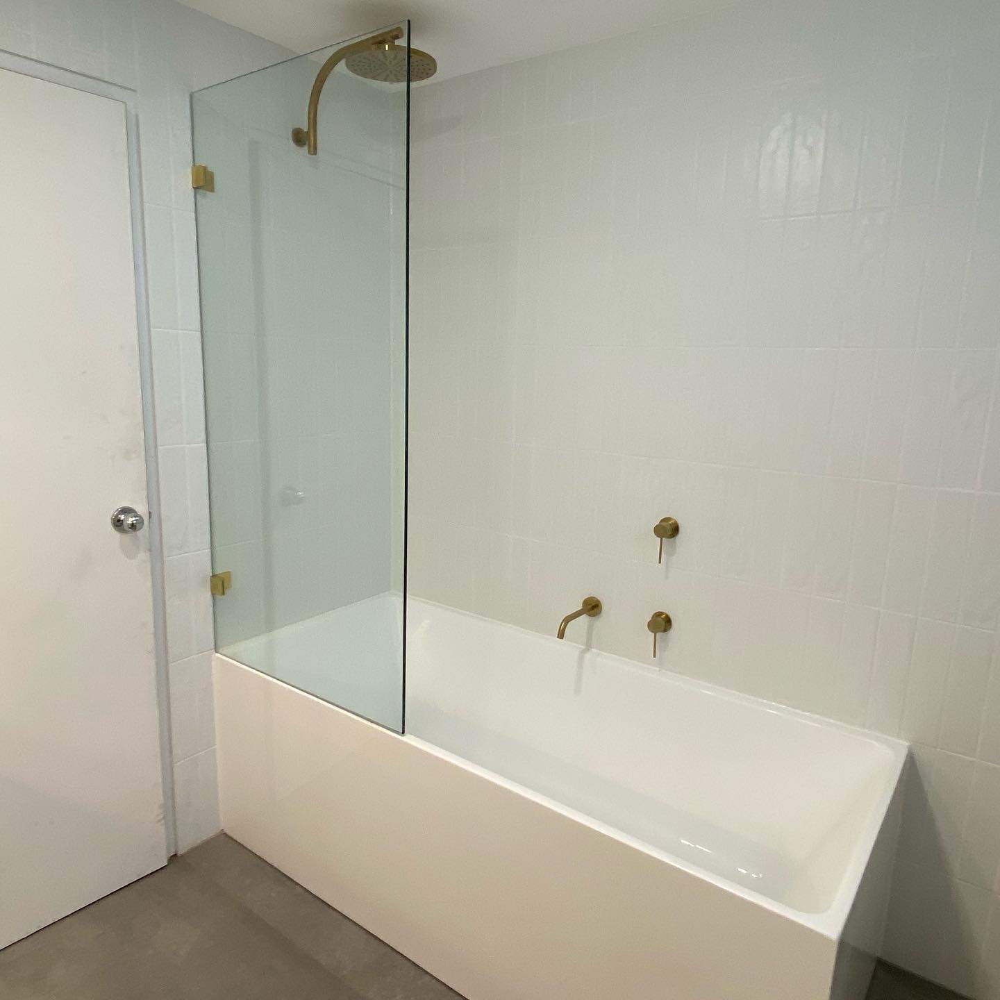 Built-in bath with a fixed glass screen and brass wall-mounted mixer and spout