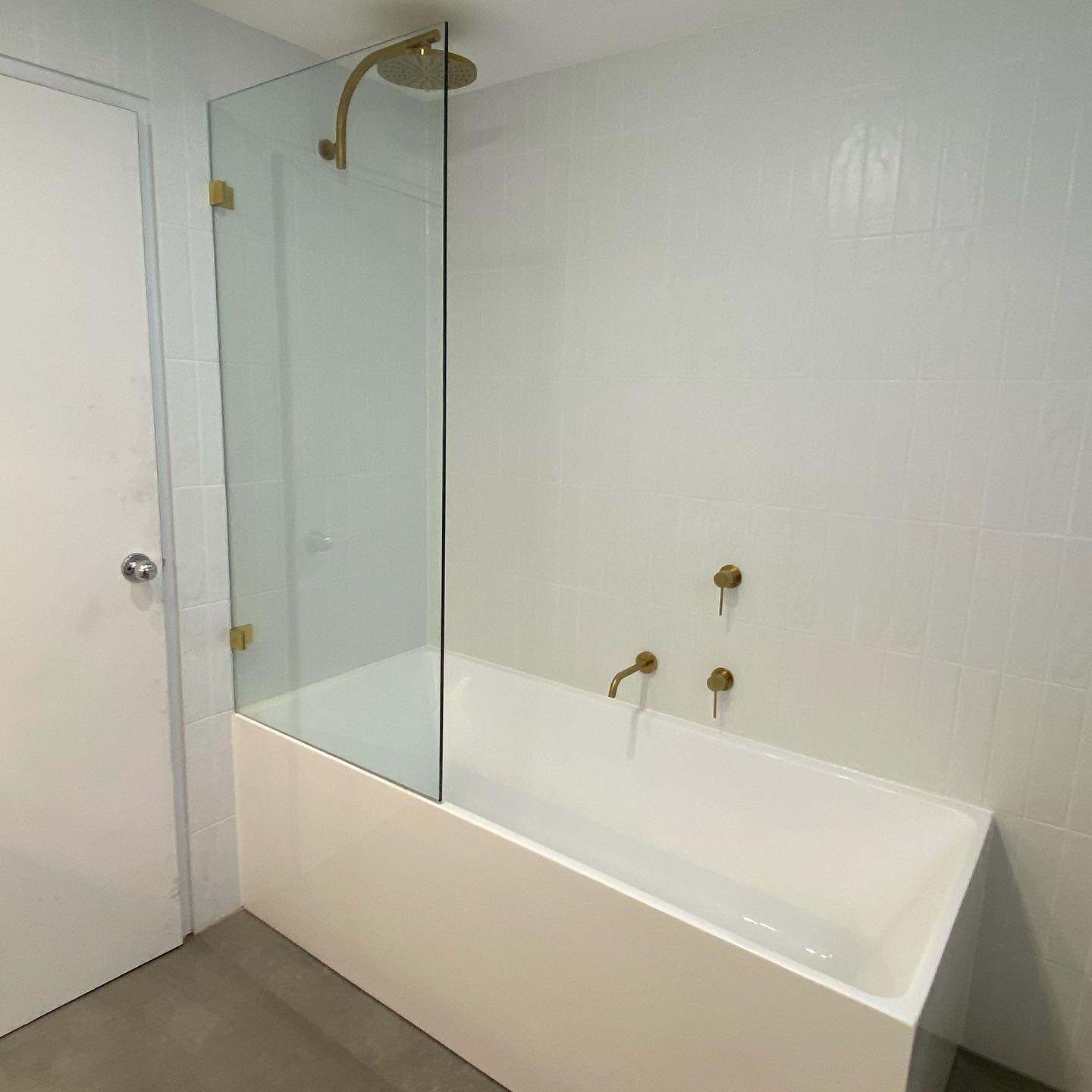 Built-in bath with a fixed glass screen and brass wall-mounted mixer and spout
