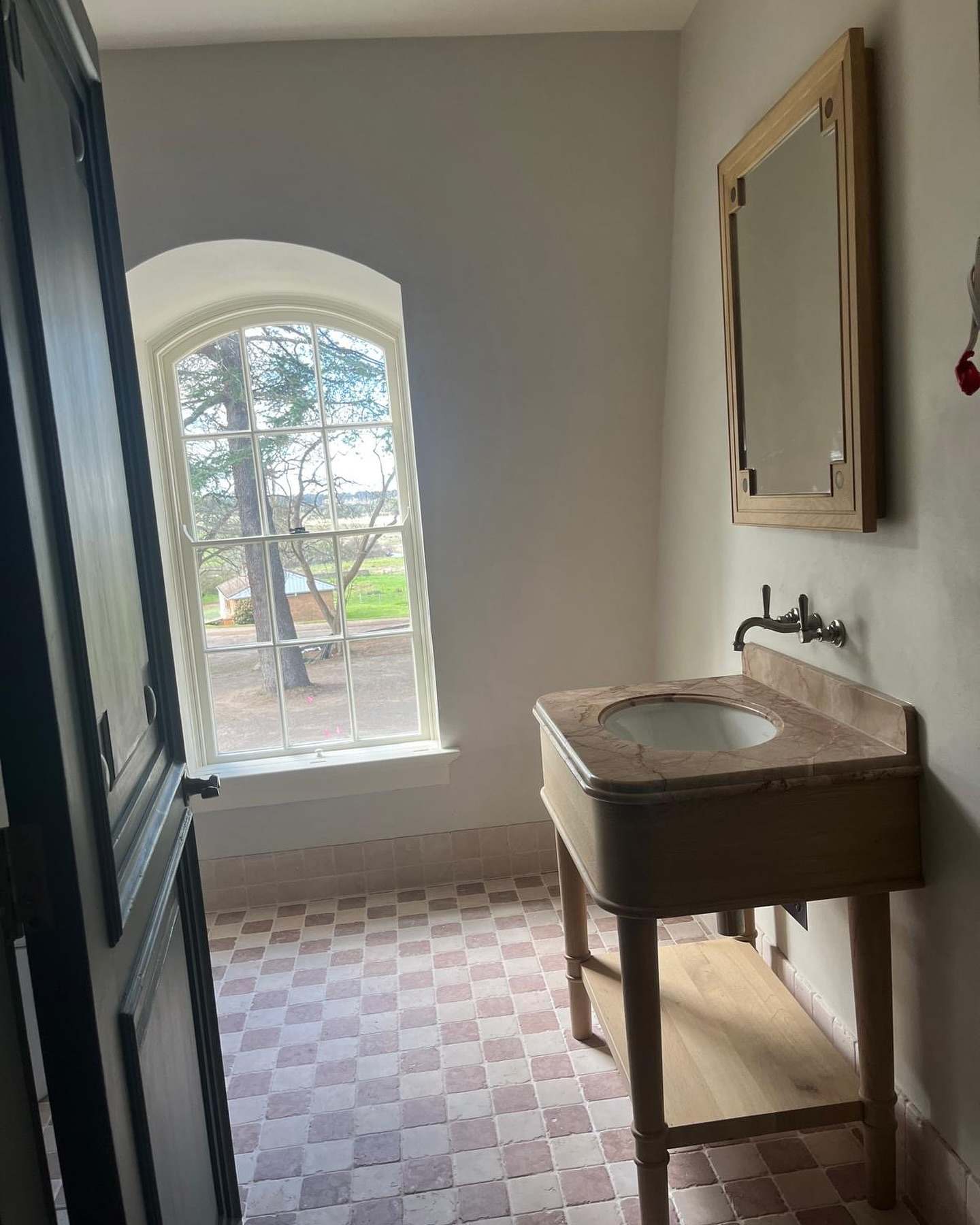 Bathroom with an arched window, checkerboard tile, timber vanity and wall-mounted taps