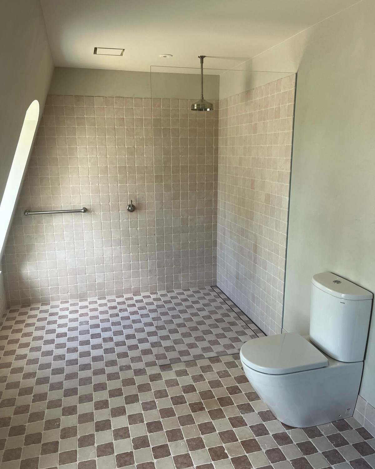 Walk-in shower with checkerboard floor tiles, square wall tiles and a ceiling-mounted rain shower