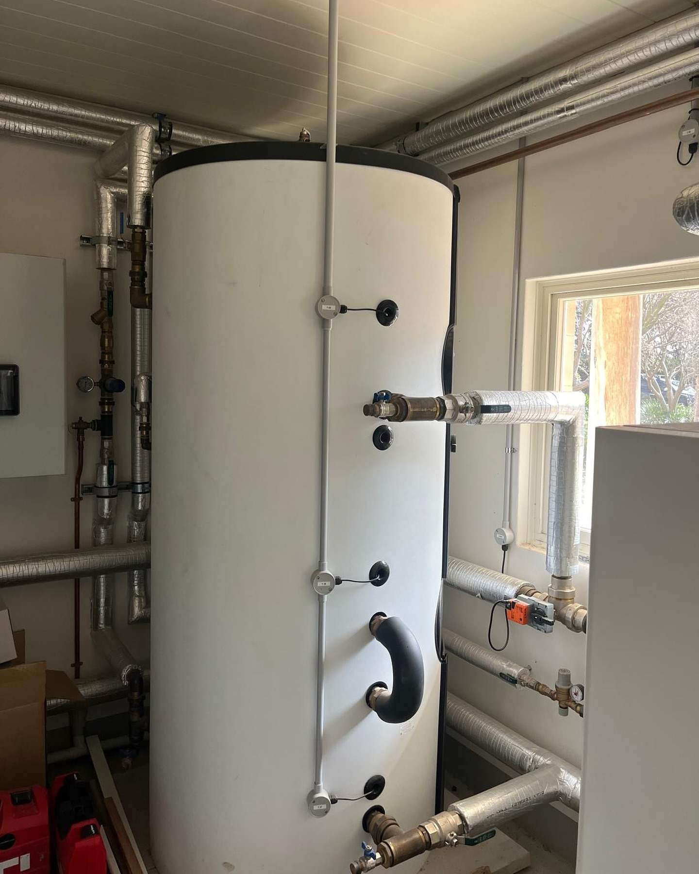 Plant room with a large hot water cylinder and copper pipework