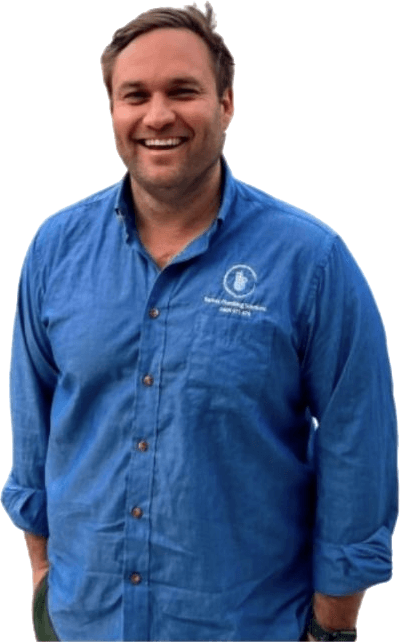 Jonathon Barnes, founder of Barnes Plumbing Solutions, smiling in a blue work shirt with Sydney Harbour behind him