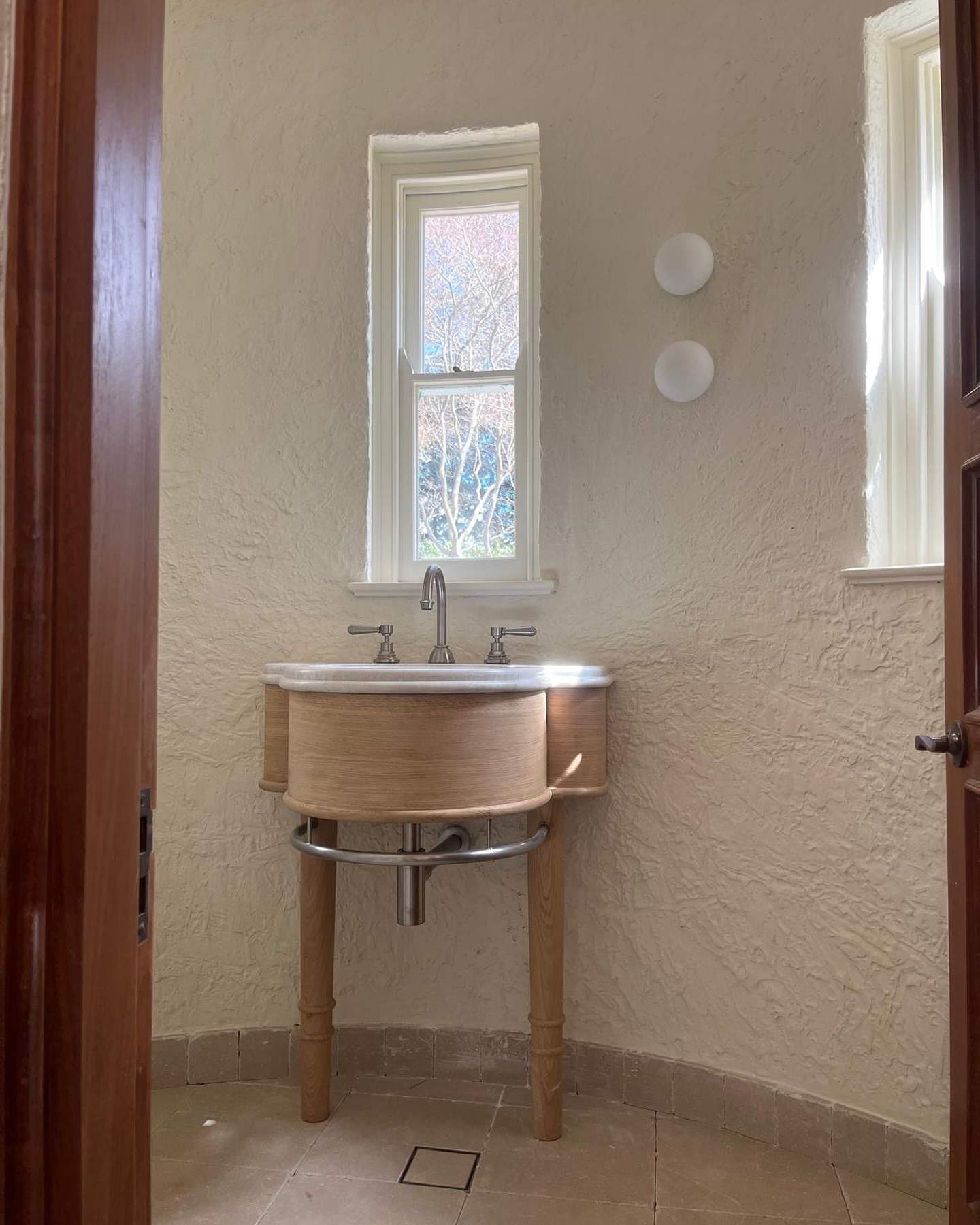 Powder room with a timber-fronted basin console and brass taps