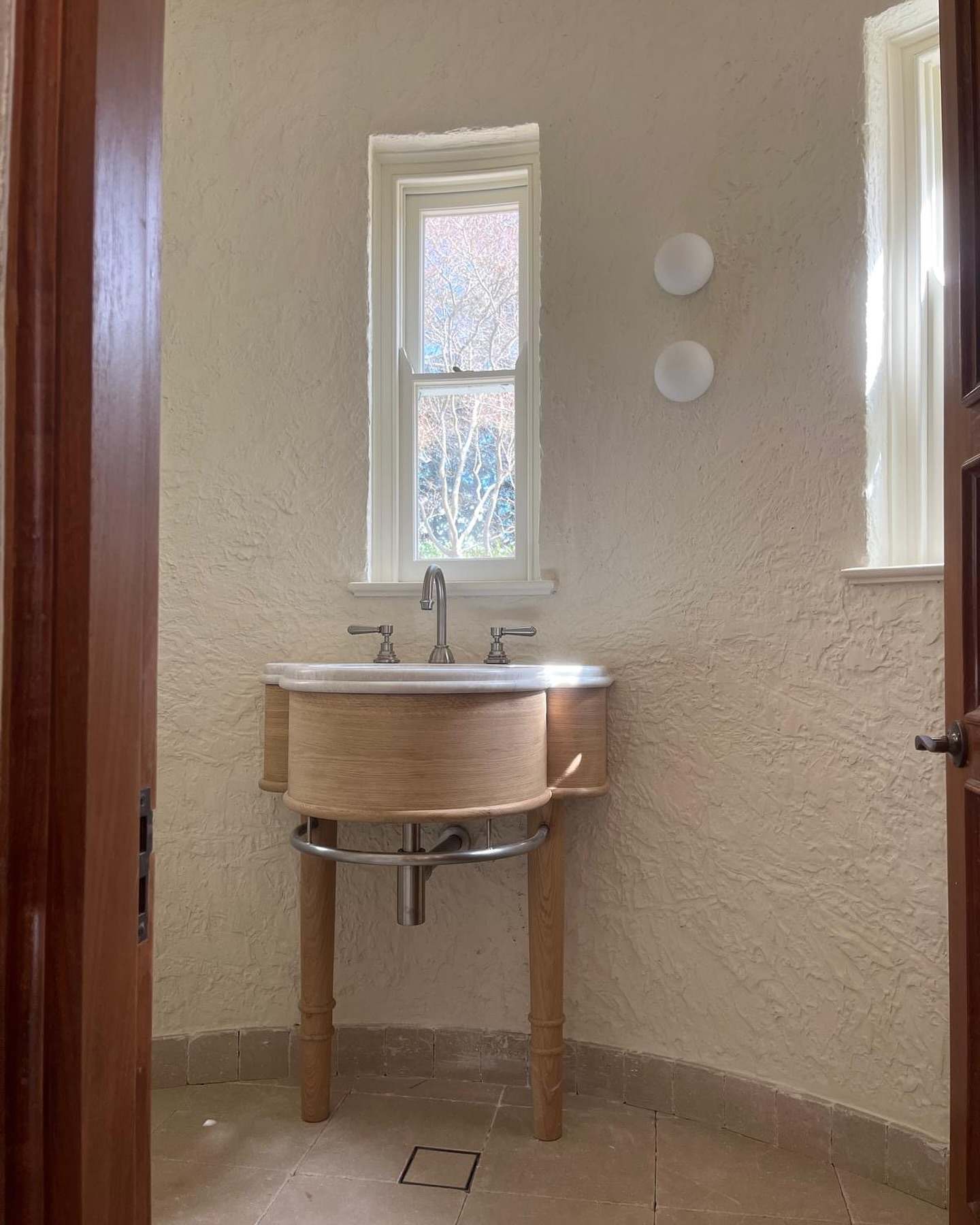 Powder room with a timber-fronted basin console and brass taps