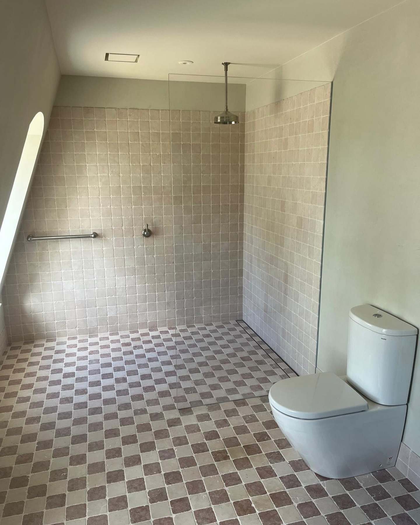Walk-in shower and toilet with a checkerboard floor